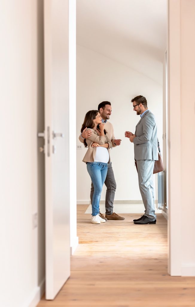 young married couple talking with a real estate agent visiting apartment for sale or for rent