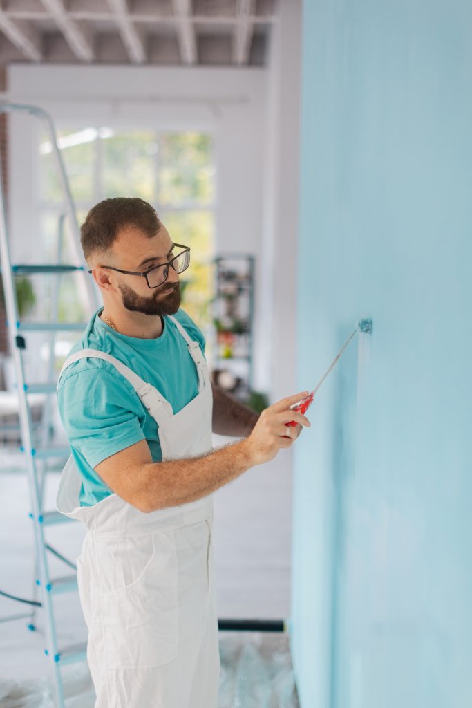 professional working diligently on a blue room wall.